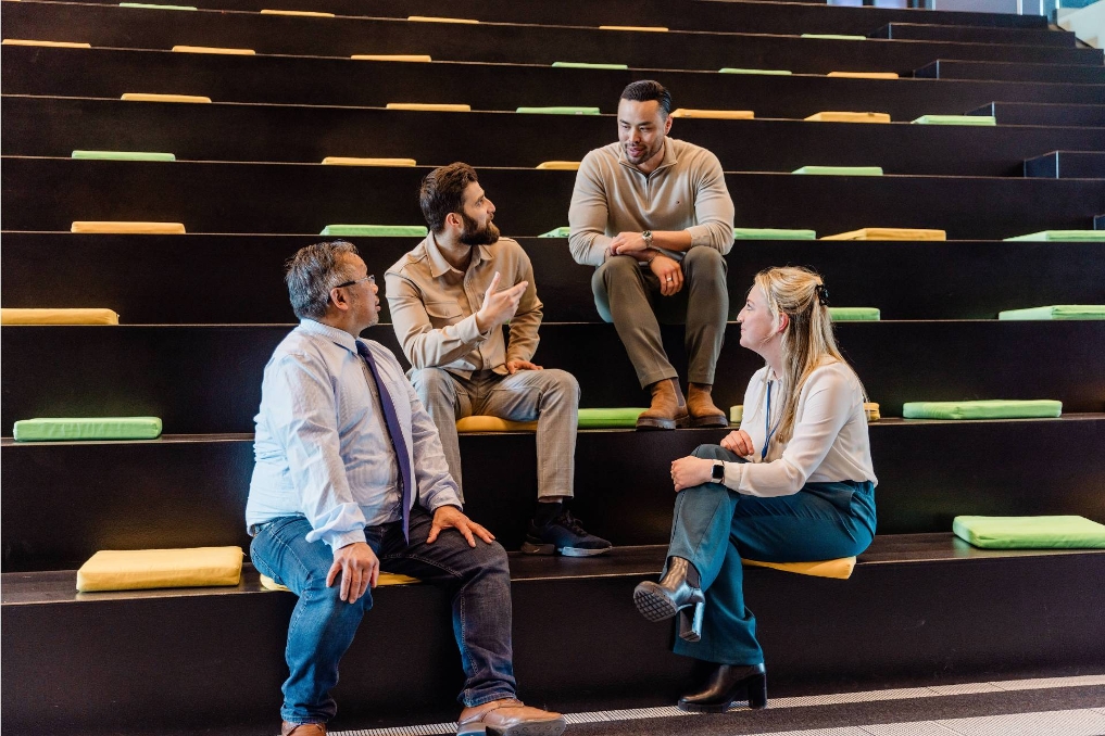 4 collega's bij het ministerie van Infrastructuur en Waterstaat overleggen op de trap. De sfeer is informeel en ongedwongen