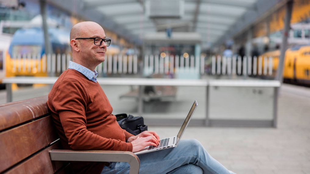 Bas is inspecteur auditor rail bij de ILT. Hier is hij aan het werk op zijn laptop op een bankje op het station