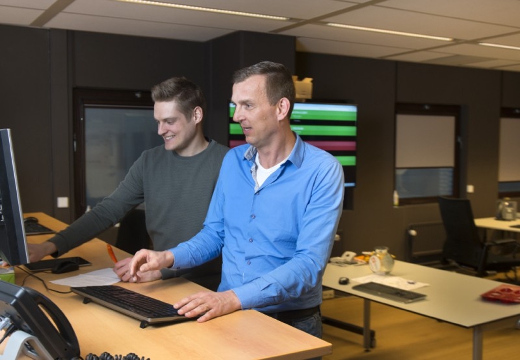 Erik met collega in gesprek achter een computer