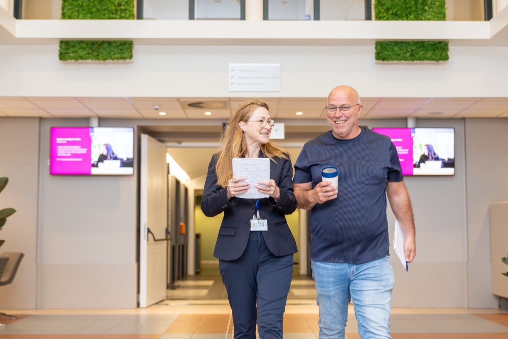 2 collega's van SZW overleggen en spreken elkaar in de gang