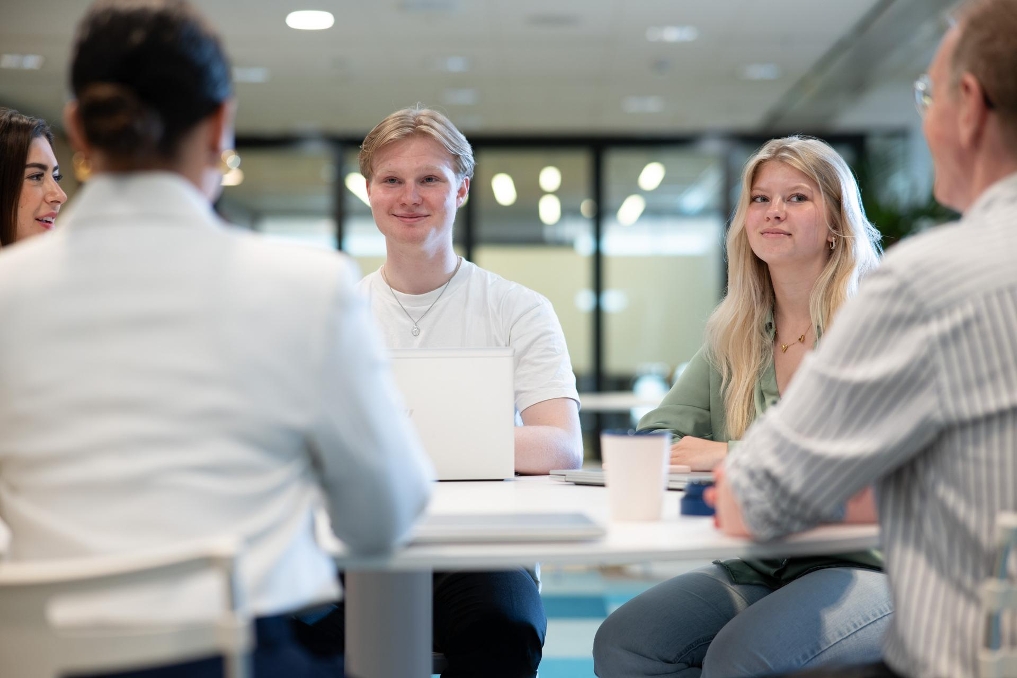 Stagiairs in overleg met elkaar aan tafel op het werk