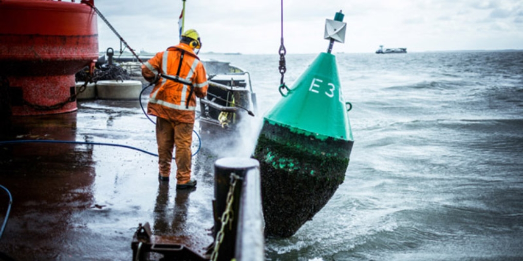Een grote groene boei wordt op zee schoongespoten.